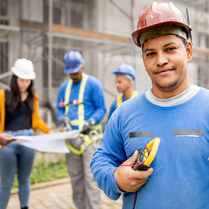 Construction electrician standing on a building site with people working in the background