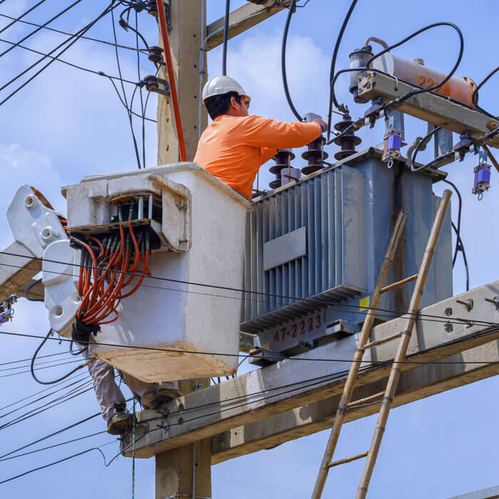 Electrician in bucket of articulated boom lift is repairing electrical transmission on power poles