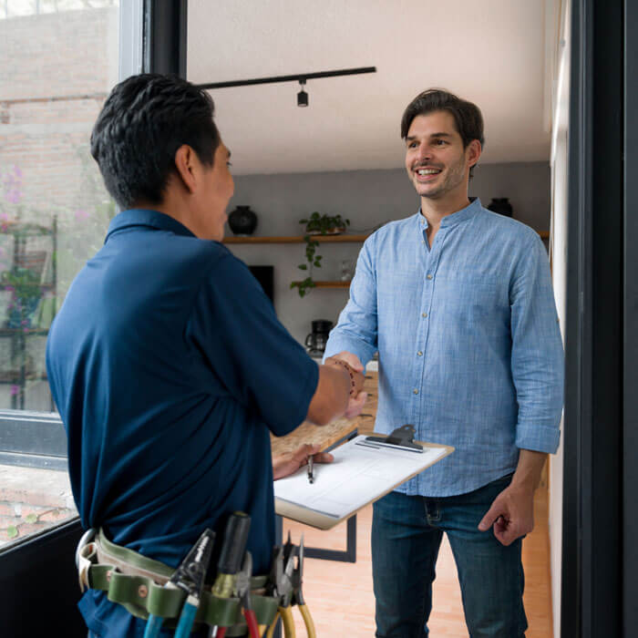 Electrician greeting a client with a handshake at the door of his house