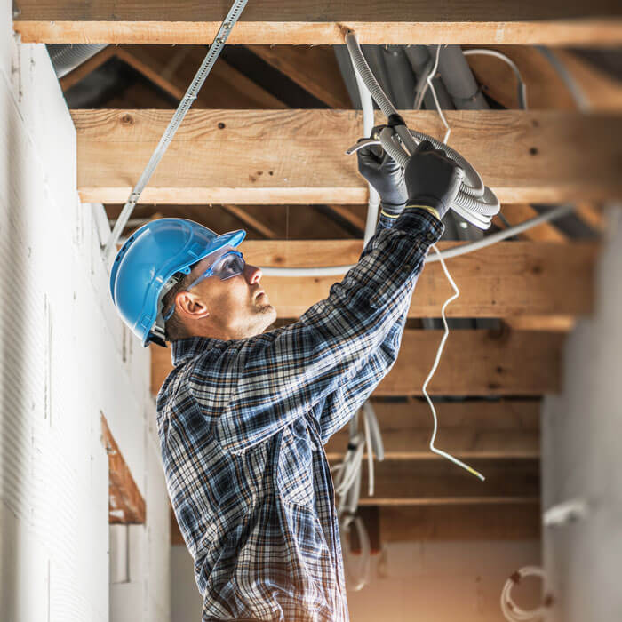 Electrician installing wiring system in the ceiling of a new building construction