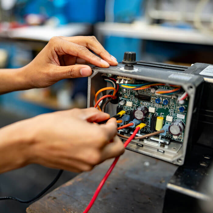 an electrician working at a manufacturing factory connecting cables to a machine