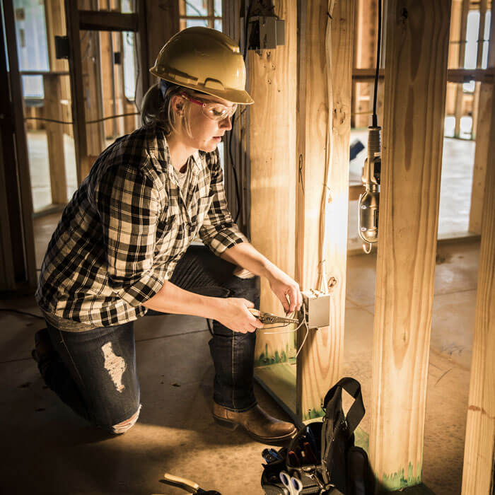 Woman electrician installing an outlet at a home construction site